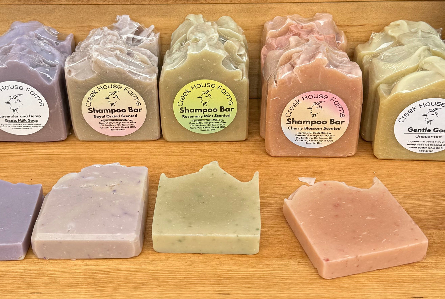 Display of various soaps with pricing on a wooden shelf.